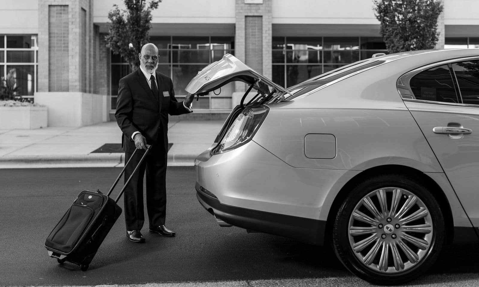 Chauffeur chargeant des bagages dans une berline